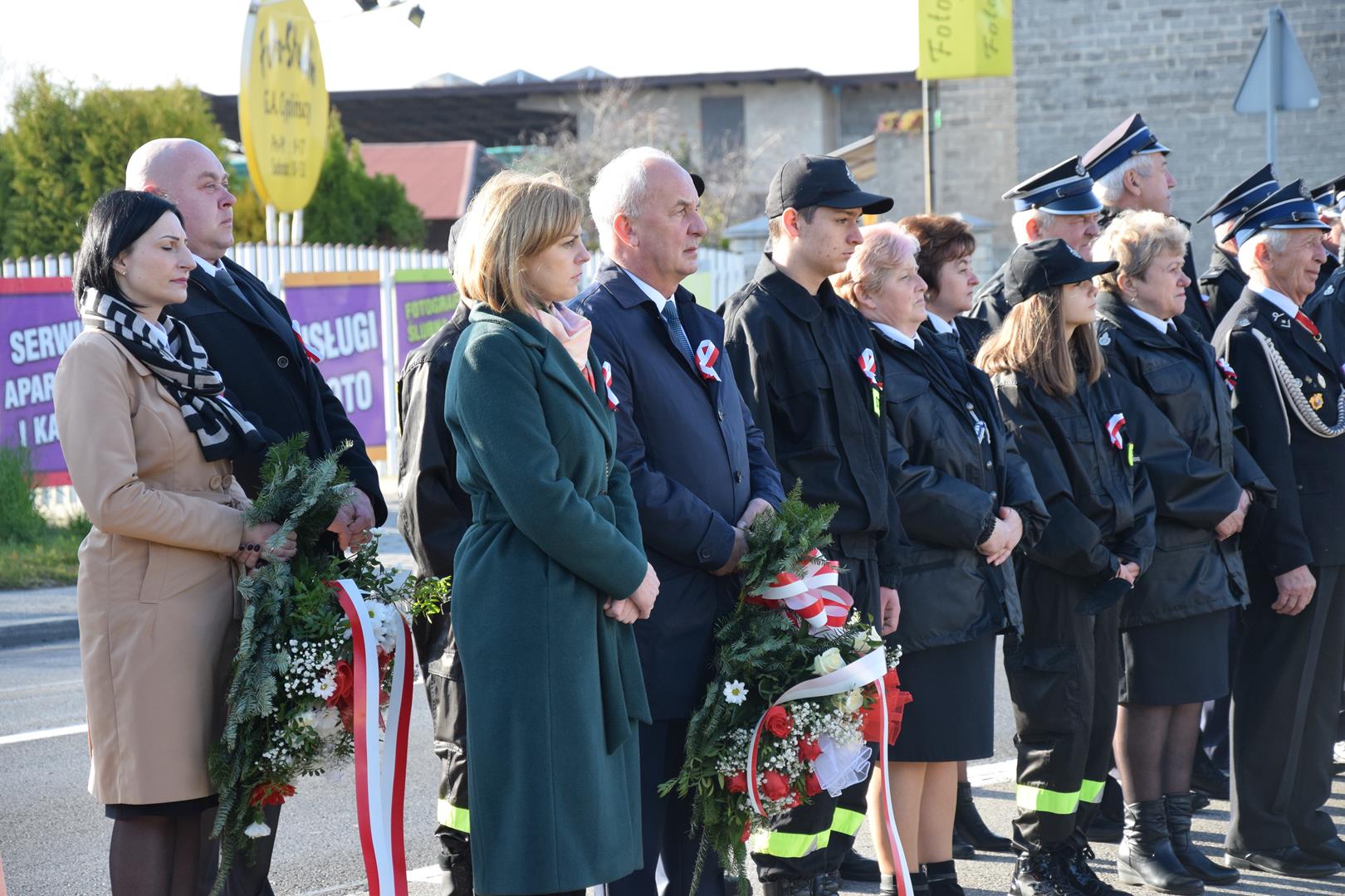 Zdjęcie z obchodów Narodowego Święta Niepodległości - władze gminy oraz radni gminy z kwiatami oraz strażacy