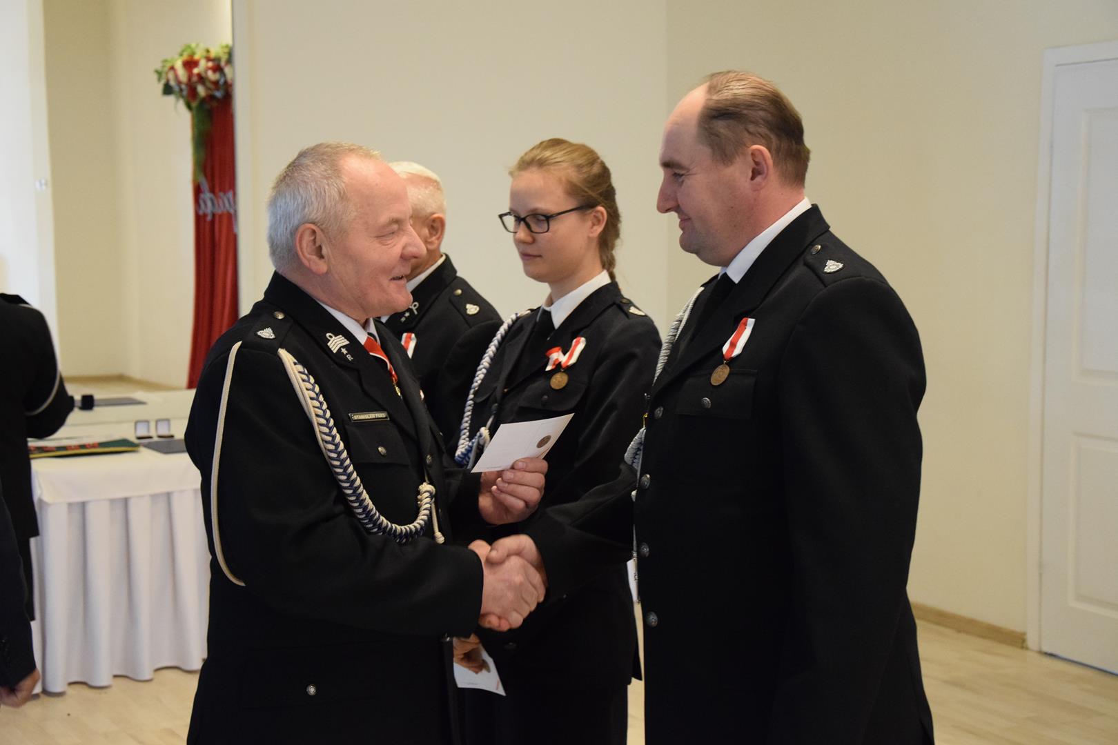 Zdjęcie przedstawia moment przyznania odznaczeń