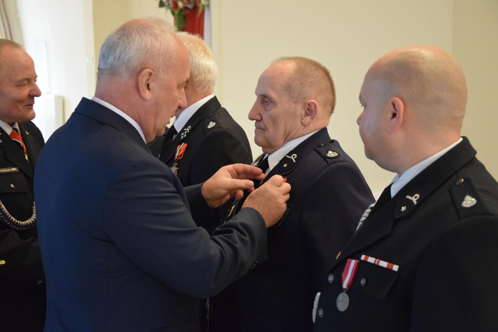 Zdjęcie przedstawia moment przyznania odznaczeń