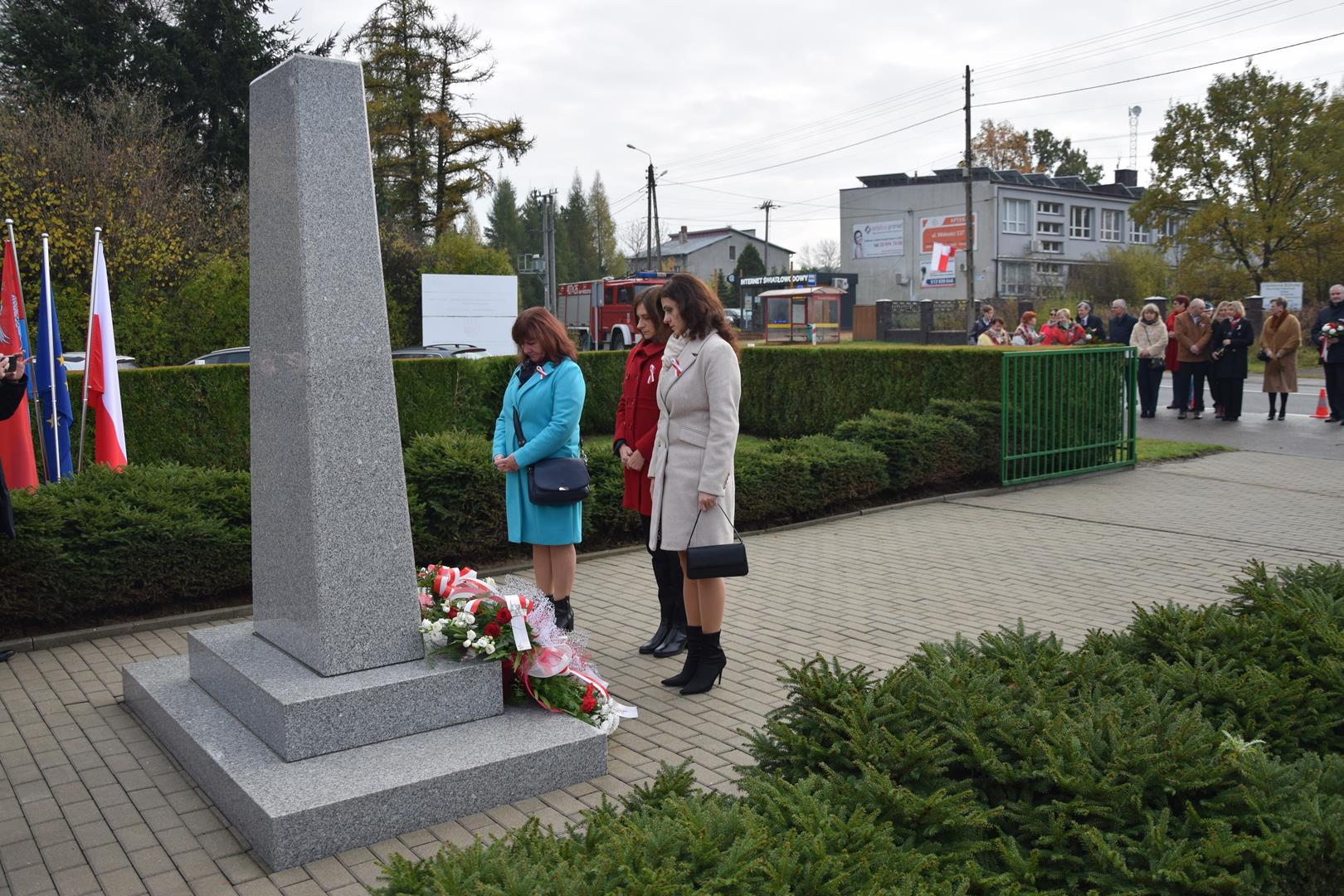 Zdjęcie przedstawia moment składania kwiatów przed pomnikiem przez reprezentantów Biblioteki Publicznej im. Jana Pawła II oraz Gminnego Ośrodka Kultury w Mierzęcicach