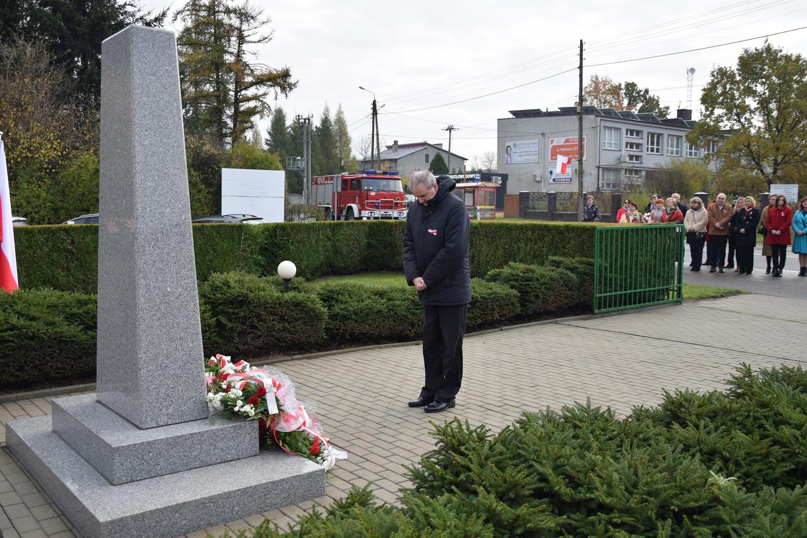 Zdjęcie przedstawia moment składania kwiatów przed pomnikiem przez Pana Roberta Białka