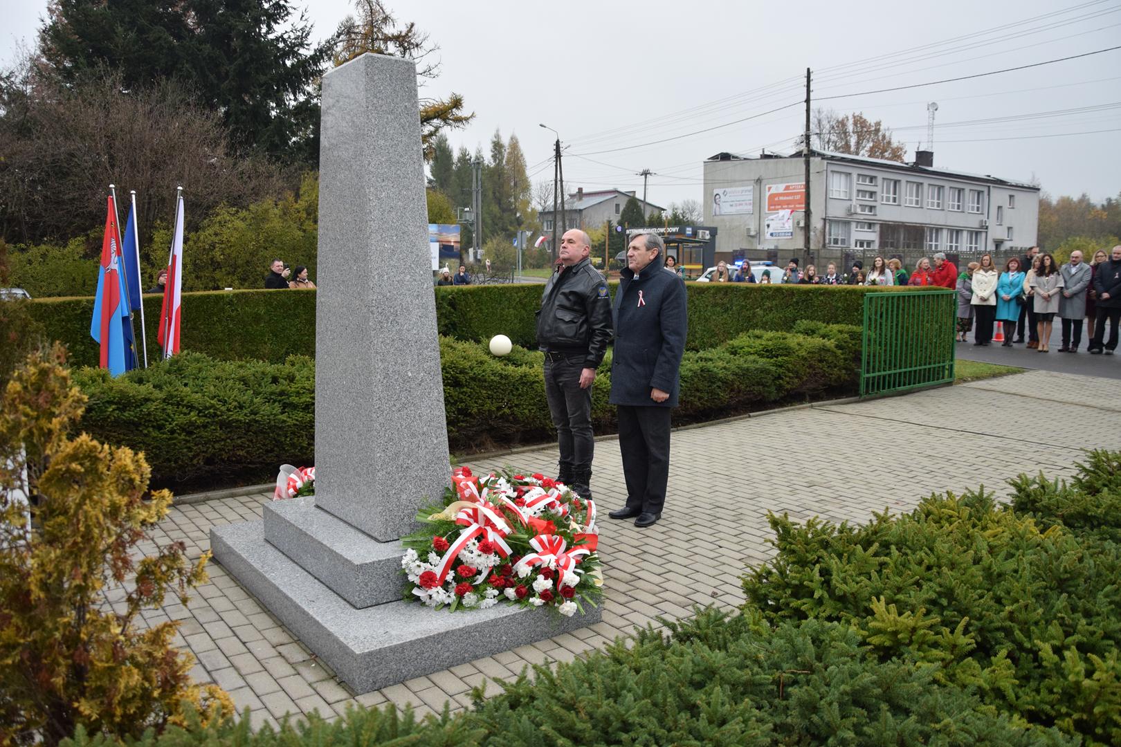 Zdjęcie przedstawia moment składania kwiatów pod pomnikiem