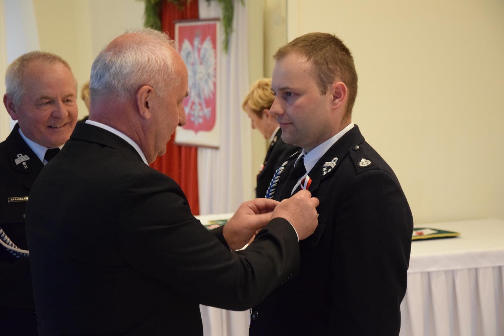 Zdjęcie przedstawia moment odznaczania zasłużonych członków straży