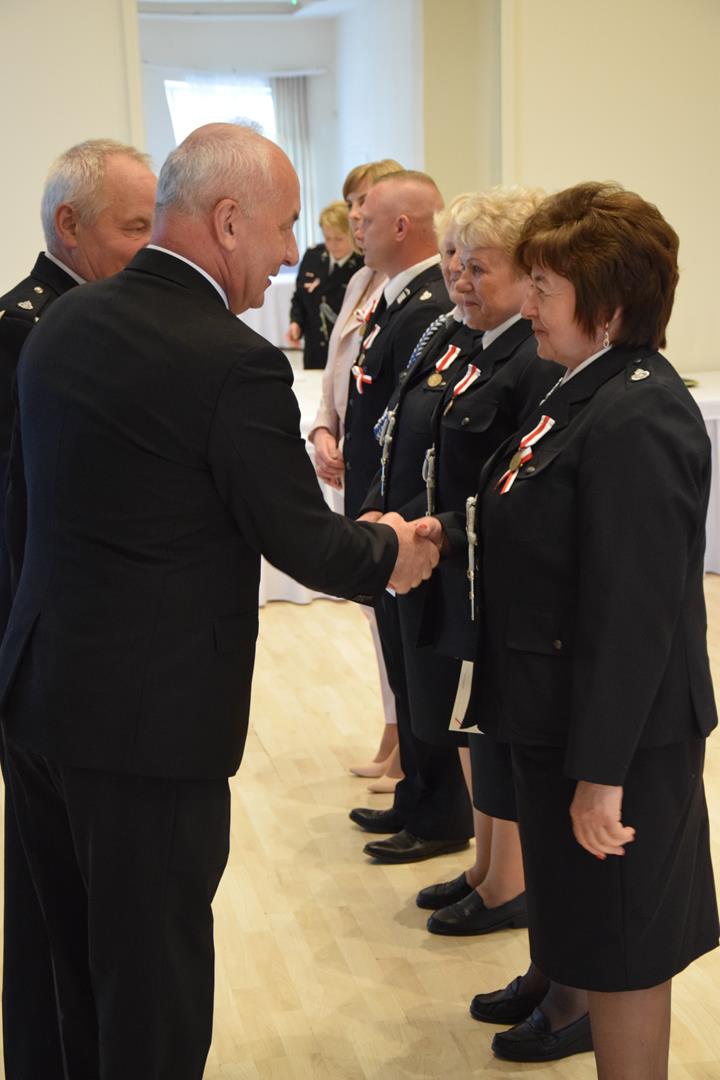 Zdjęcie przedstawia moment odznaczania zasłużonych członków straży