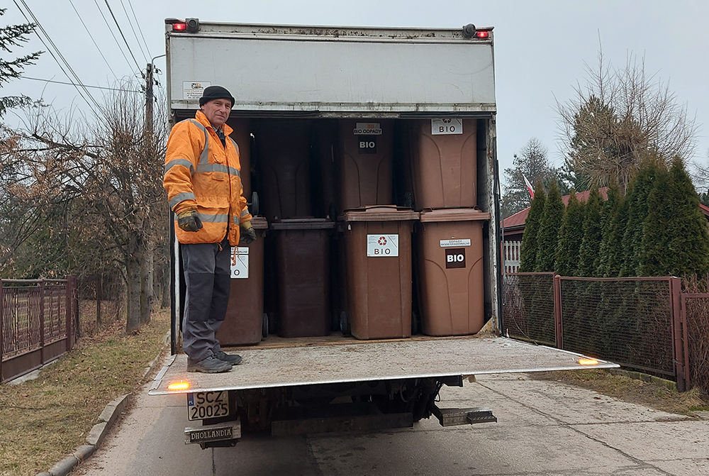 Zdjęcie przedstawiające samochód z pojemnikami na bioodpady oraz pracownika firmy gospodarującej odpadami na terenie gminy Mierzęcice