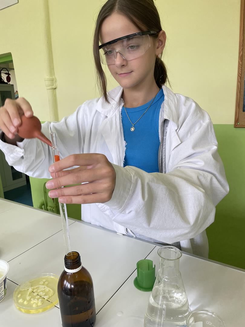 Zdjęcie przedstawia dziewczynkę przeprowadzającą eksperymenty