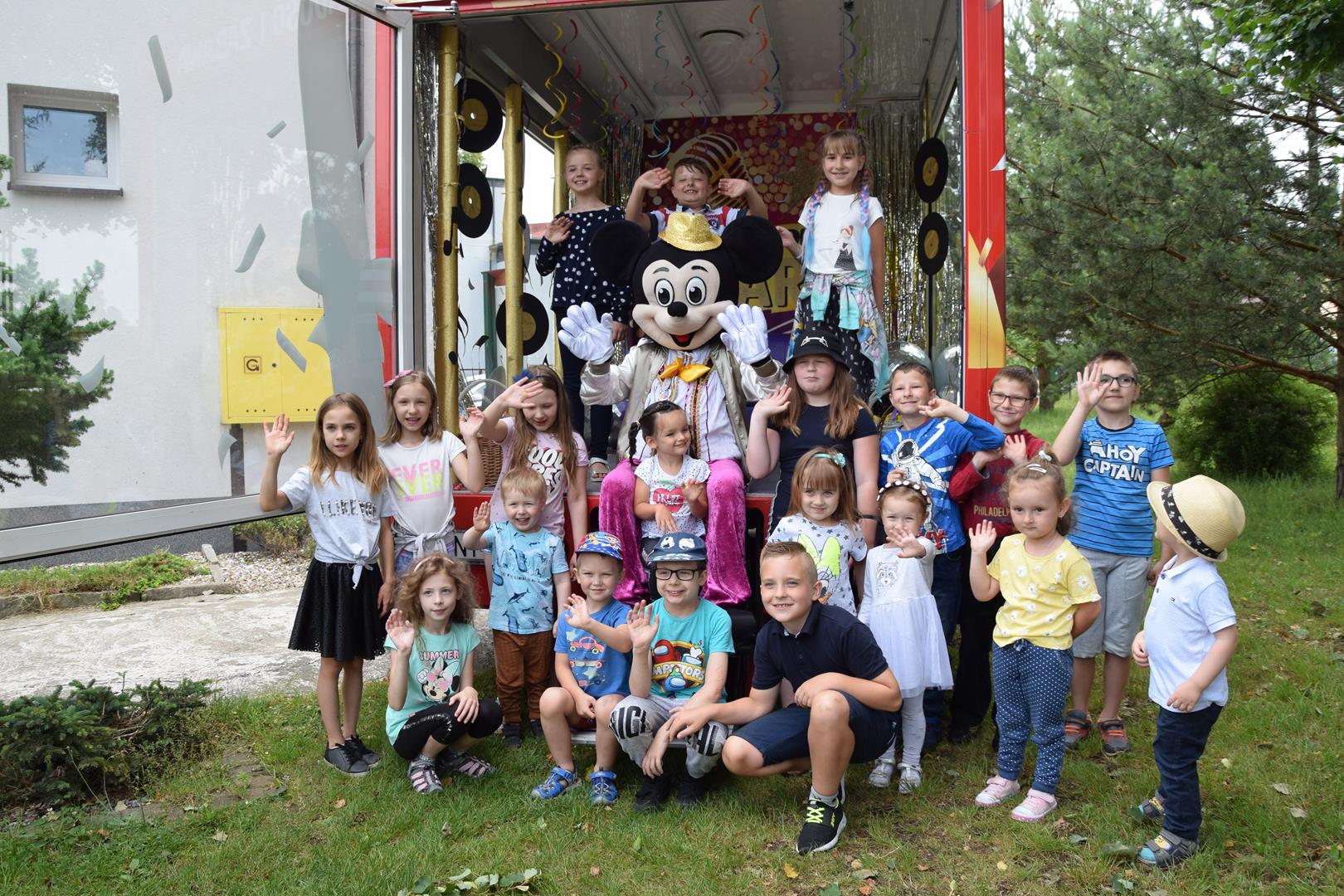 Zdjęcie przedstawiające dzieci pozujących z Myszką Miki na tle Discobusa