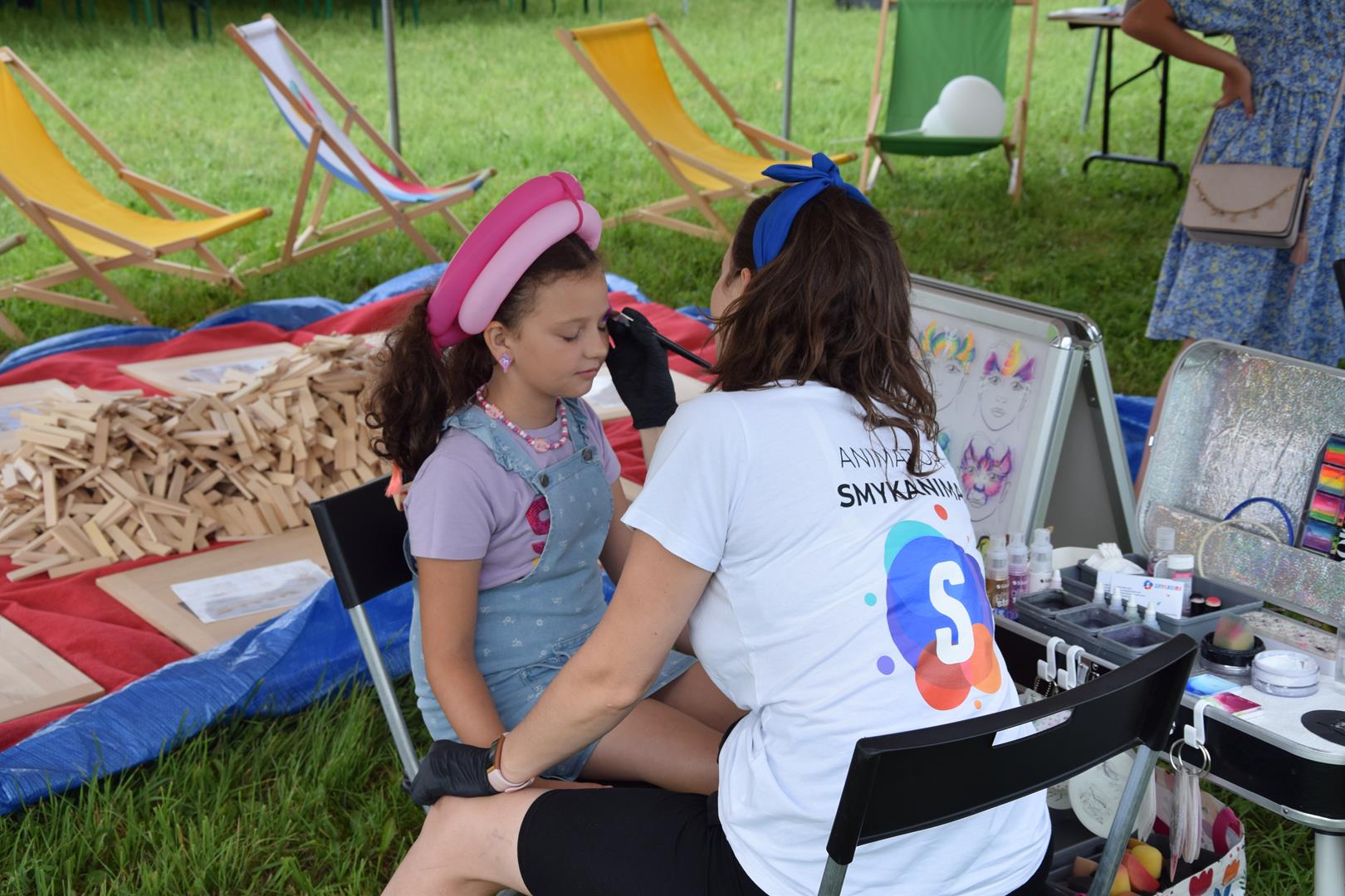 Zdjęcie przedstawia malowanie twarzy przy stosiku z animacjami dla dzieci