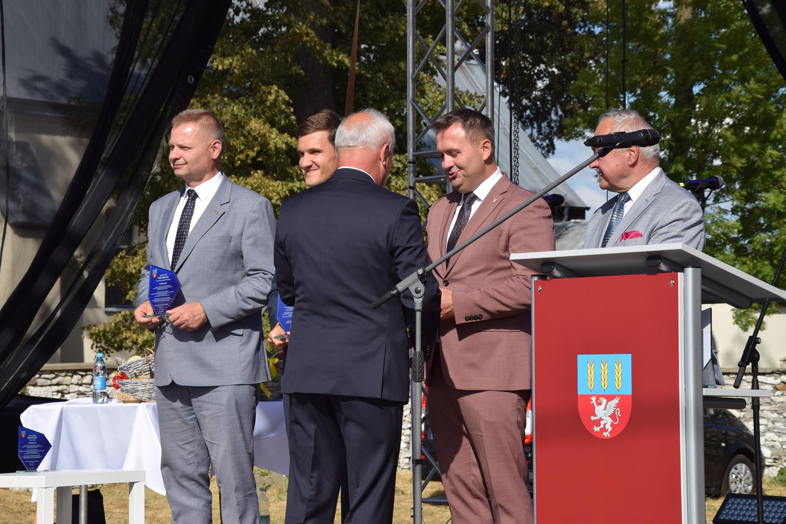 Zdjęcie przedstawia moment wręczenia pamiątkowych grawertonów