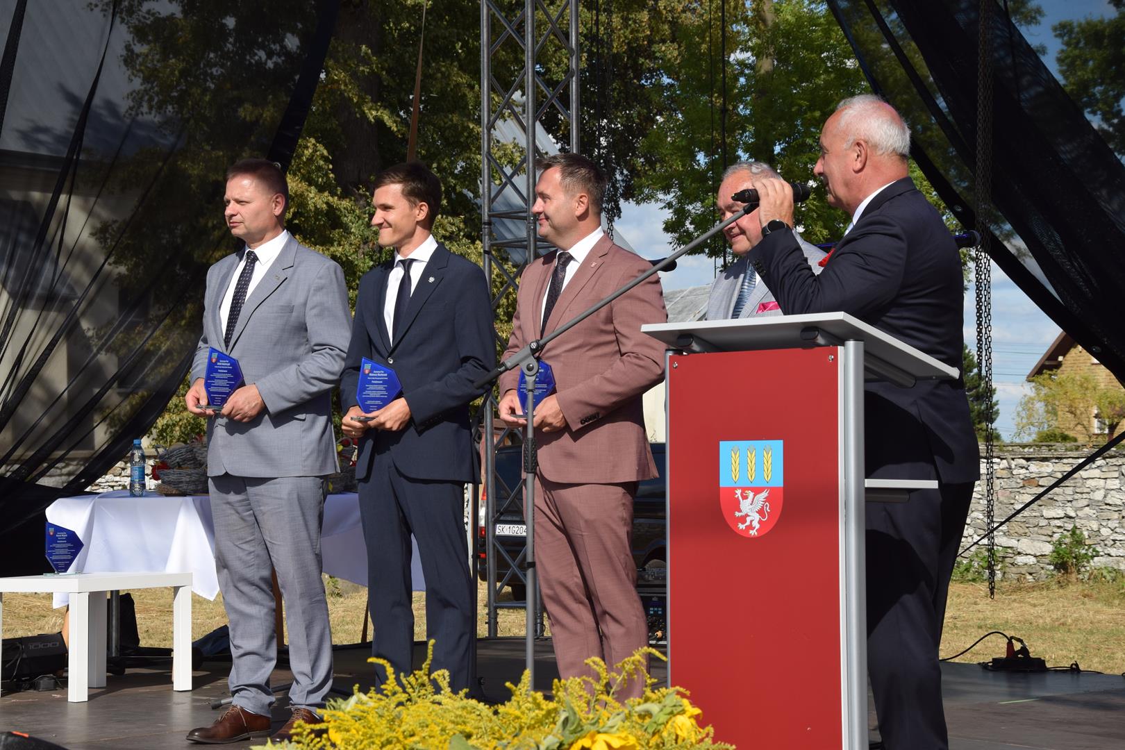 Zdjęcie przedstawia moment wręczenia pamiątkowych grawertonów