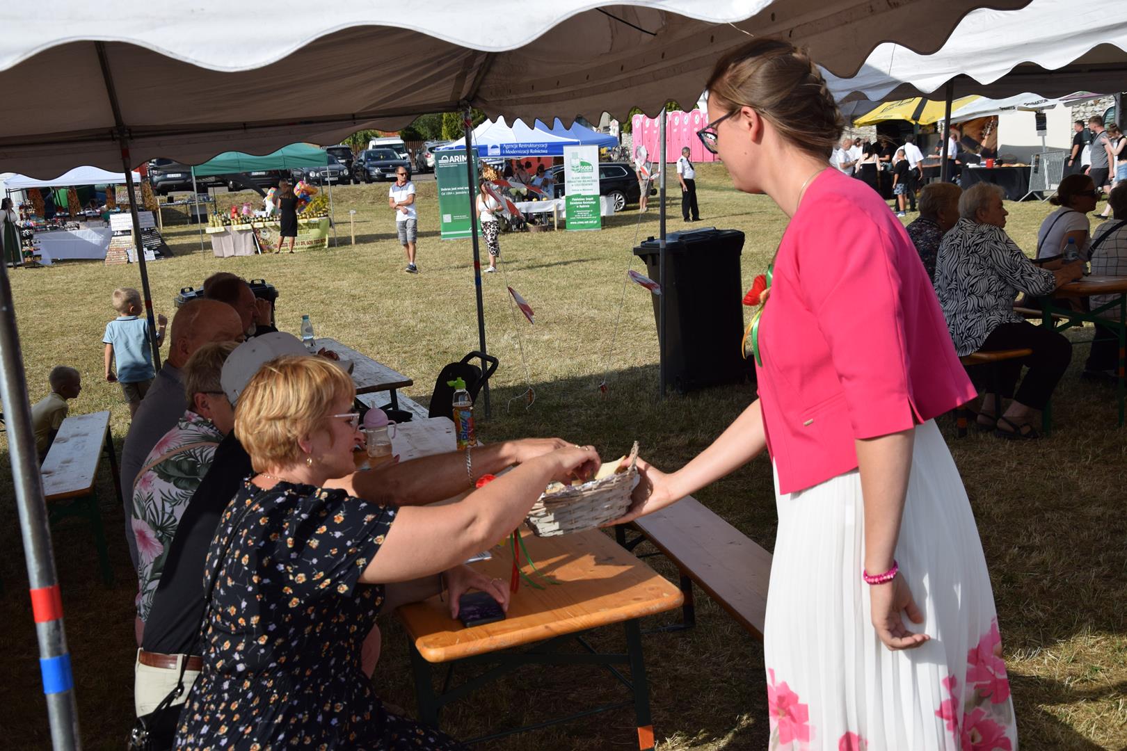 Zdjęcie przedstawia dzielenie się chlebem dożynkowym z&nbsp;uczestnikami dożynek