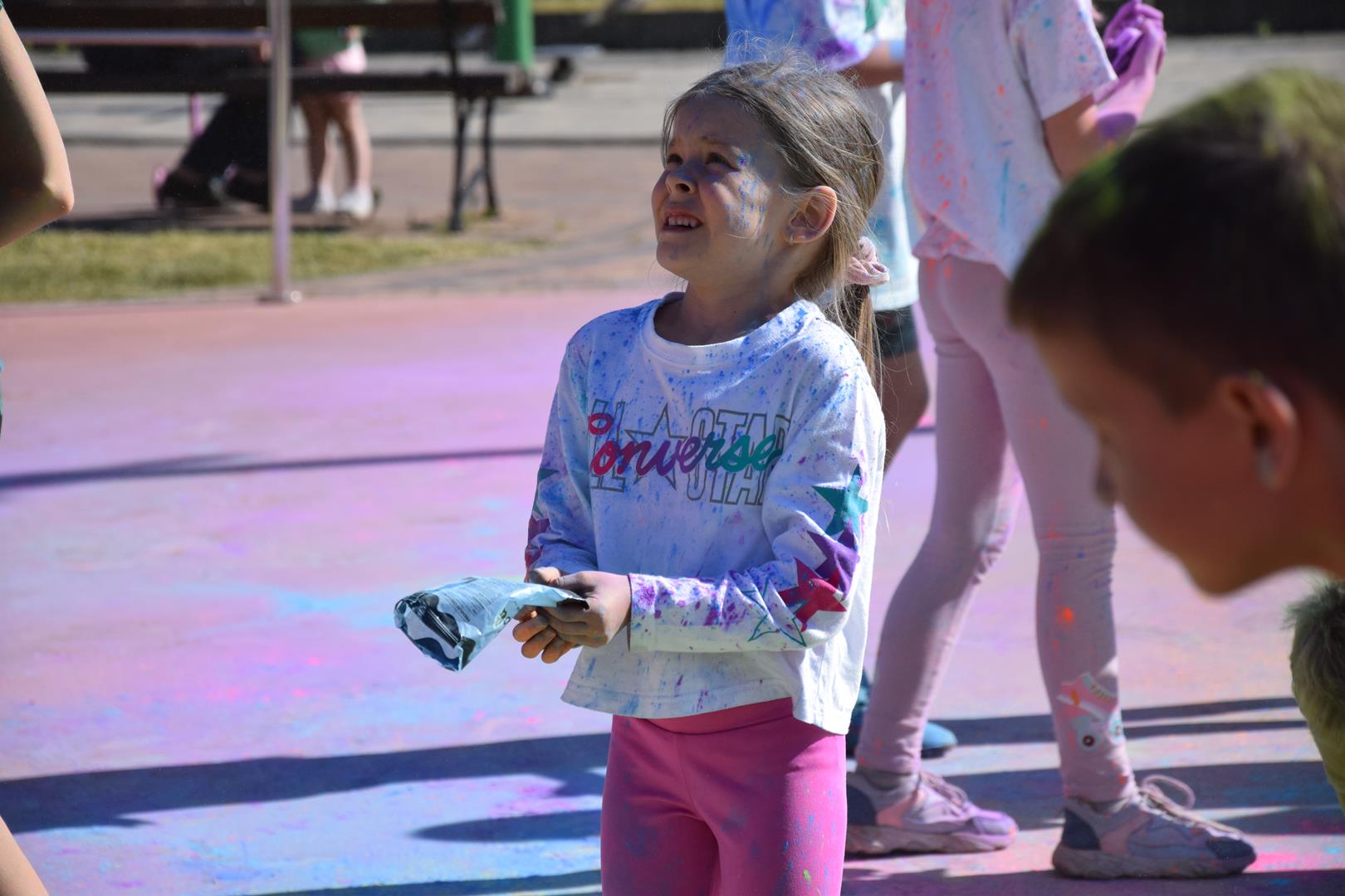 Zdjęcie przedstawiające dziecko rzucające proszkami holi