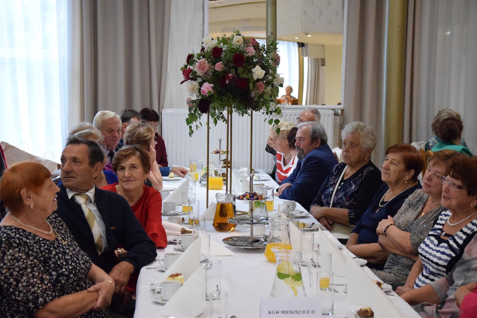 Zdjęcie przedstawia ludzi siedzących przy stoliku