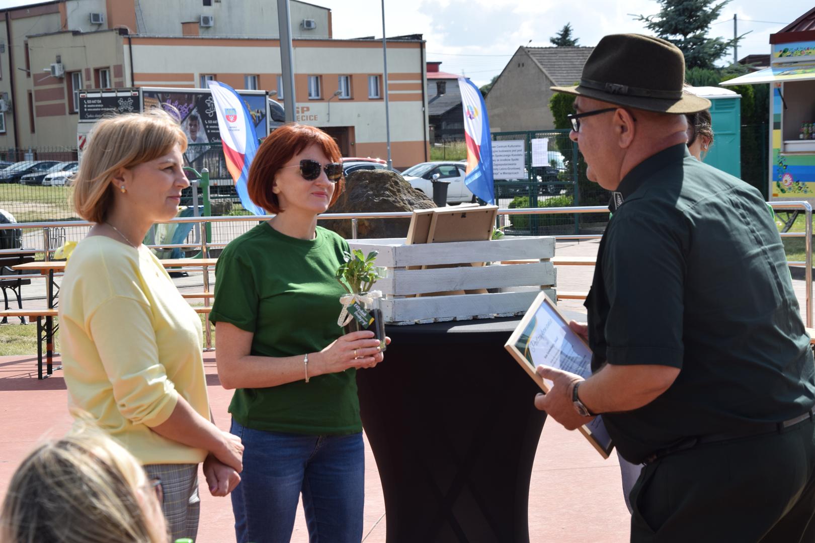 Zdjęcie przedstawia moment wręczenie pamiątkowych eko prezentów dla wystawców