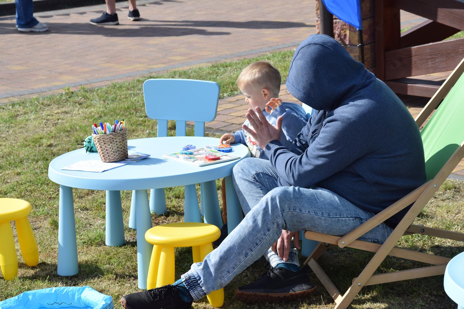 Zdjęcie przedstawia dziecko oraz mężczyznę na leżakach