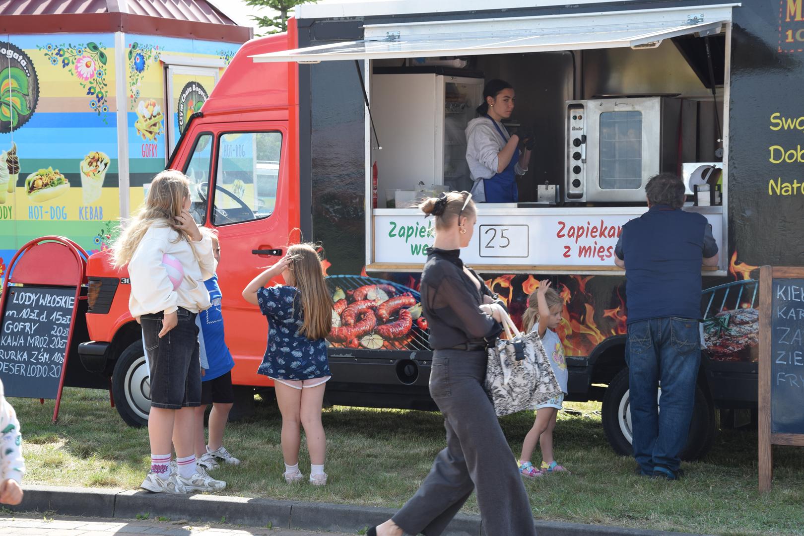 Zdjęcie przedstawia uczestników pikniku korzystających z&nbsp;oferty foodtrucków