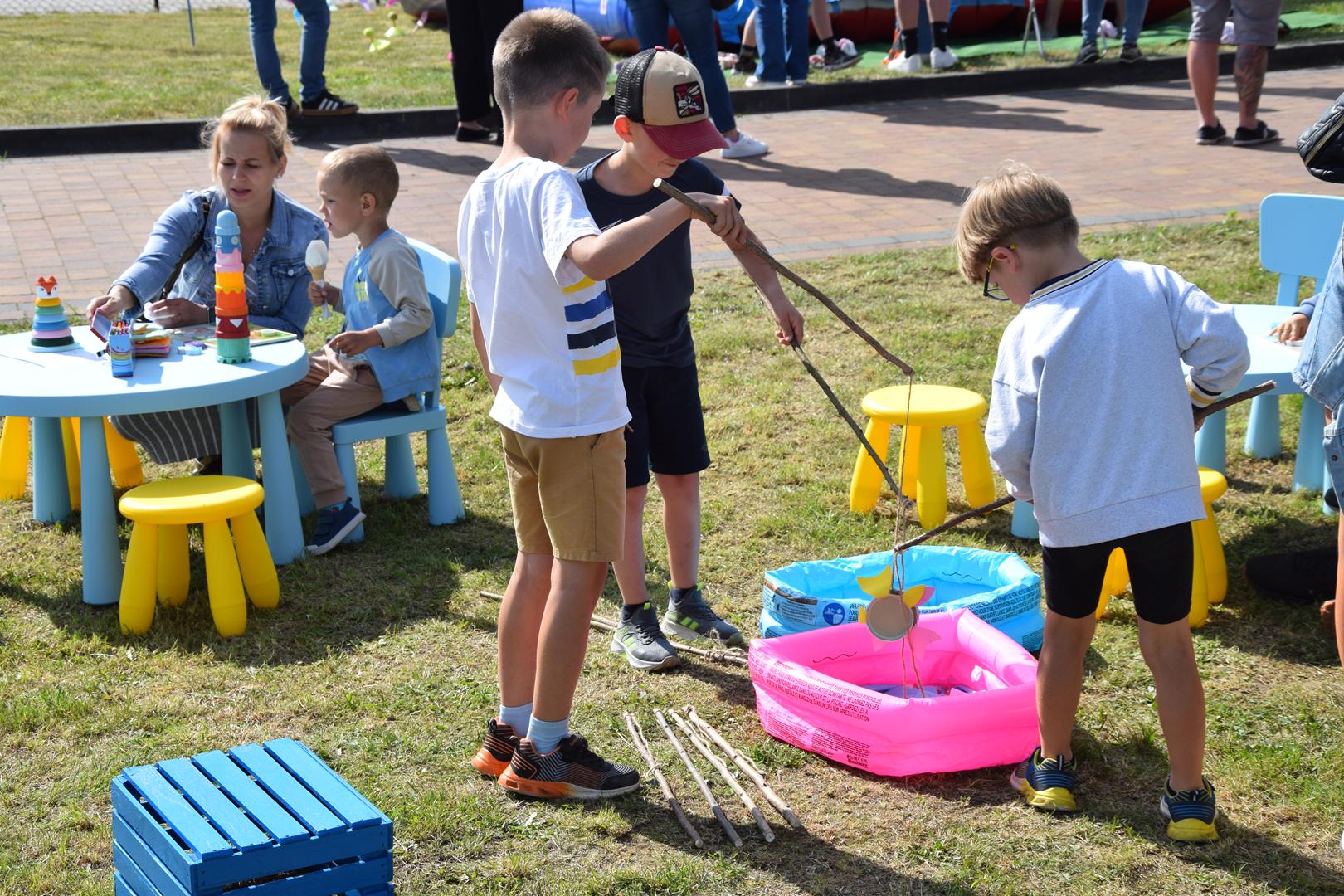 Zdjęcie przedstawia dzieci bawiące się wędkami z&nbsp;magnesem podczas pikniku ekolgicznego