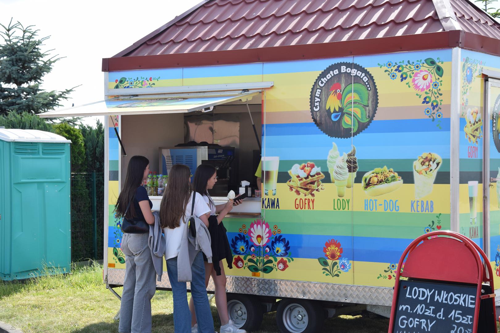 Zdjęcie przedstawia uczestników pikniku korzystających z&nbsp;oferty foodtrucków