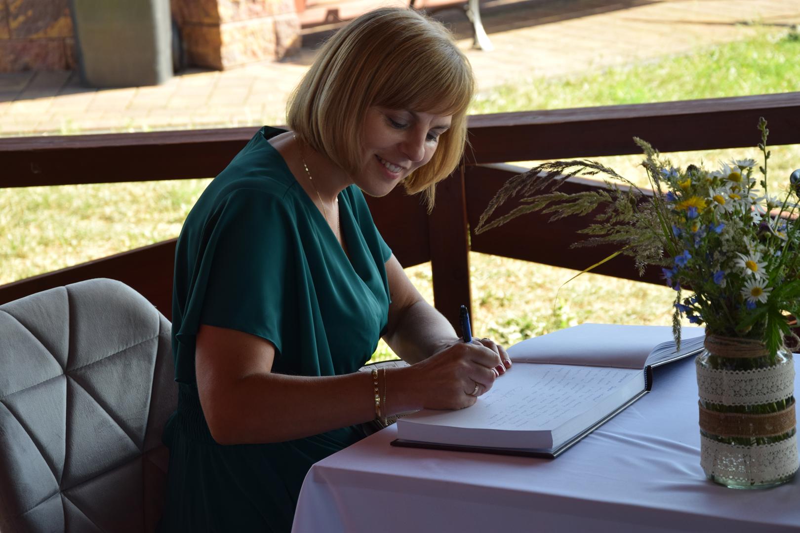 Zdjęcie przedstawia Skarbnik Gminy Mierzęcice Agnieszkę Frączek dokonującej wpisu do księgi pamiątkowej