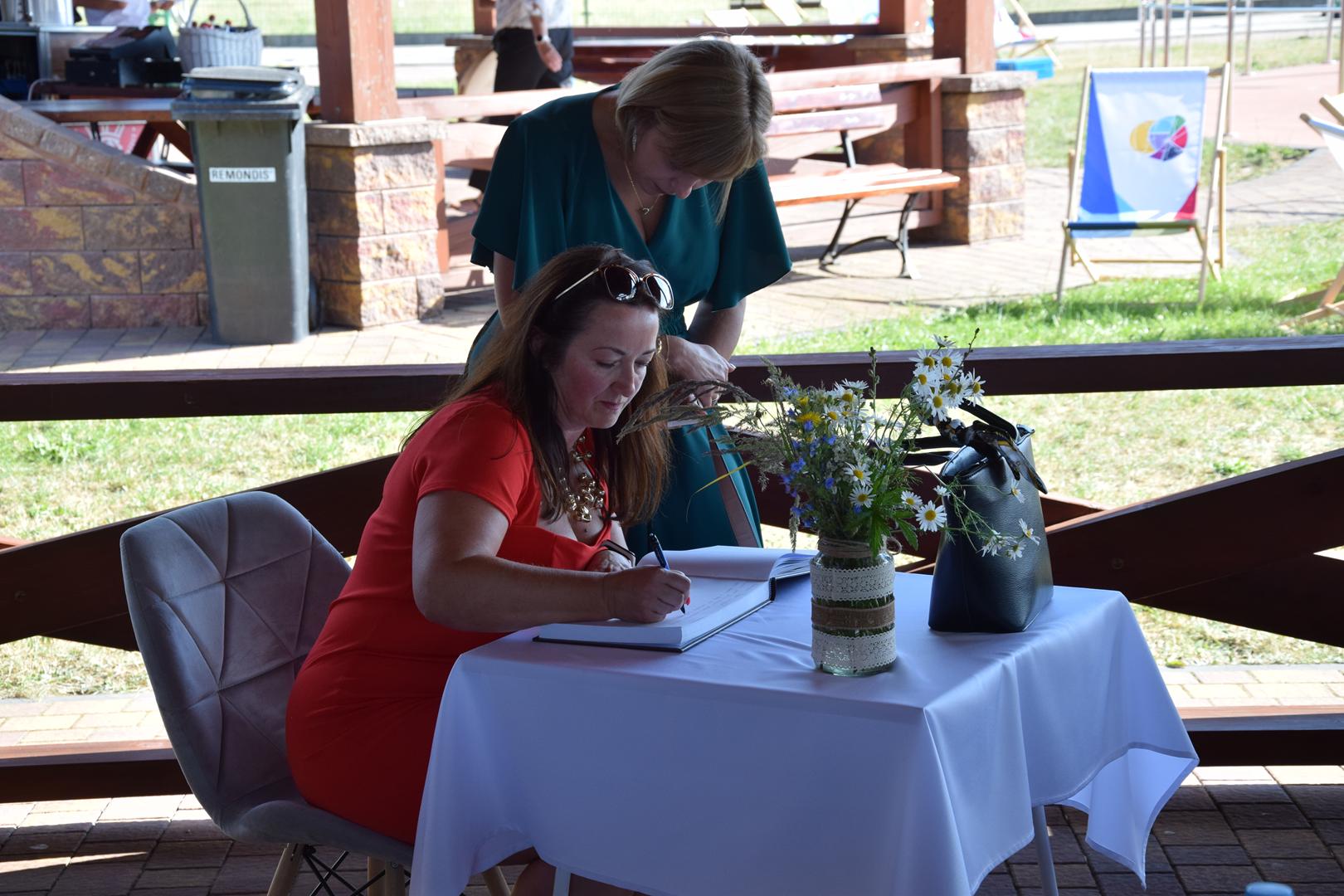 Zdjęcie przedstawia Wicewójt Gminy Mierzęcice Iwonę Pańta dokonującej wpisu do księgi pamiątkowej