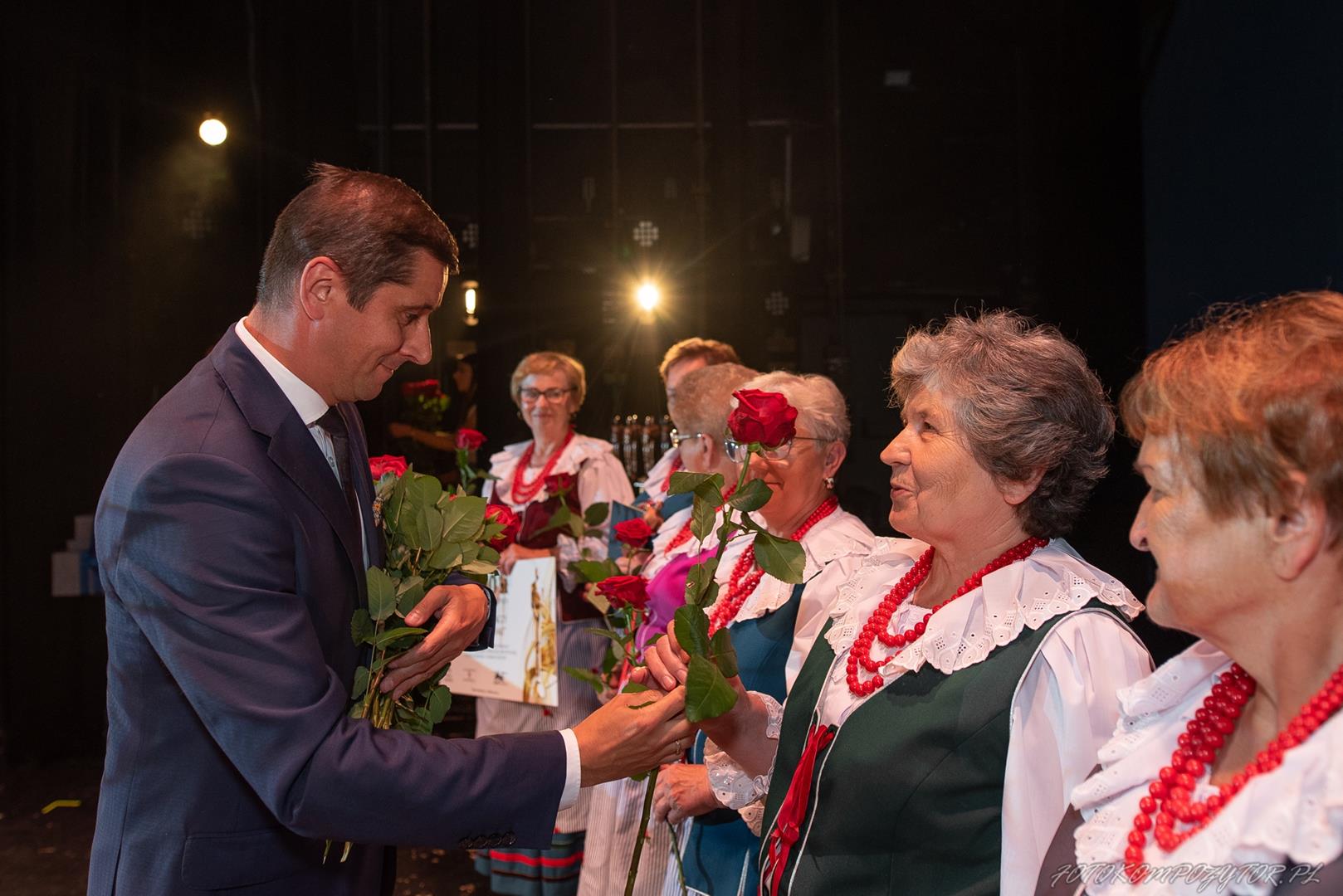Zdjęcie przedstawia moment rozdania kwiatów podczas uroczystości