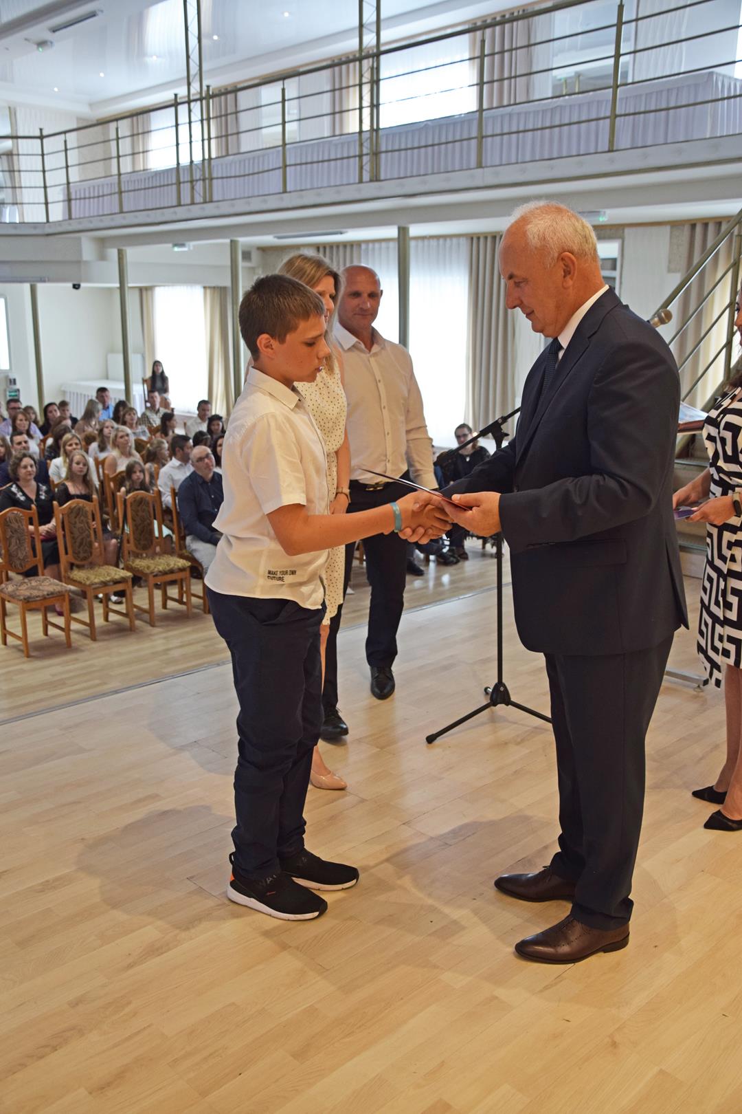 Zdjęcie przedstawia ucznia odbierającego nagrodę wójta