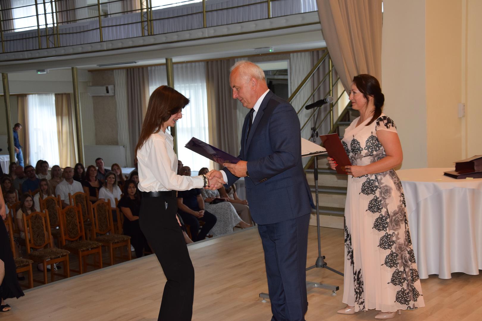 Zdjęcie przedstawia moment wręczenia dyplomów z okazji promocji ucznia zdolnego 2024