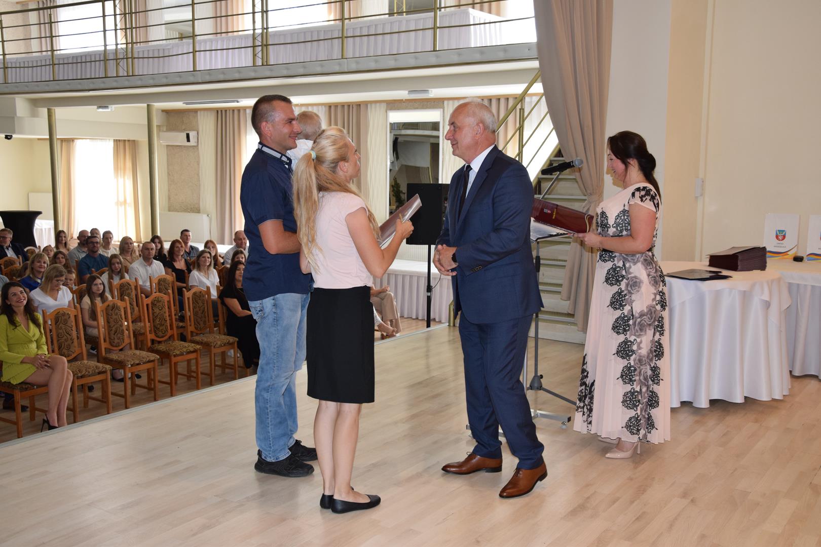 Zdjęcie przedstawia moment wręczenia dyplomów z okazji promocji ucznia zdolnego 2024