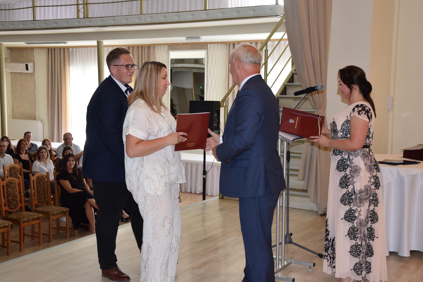 Zdjęcie przedstawia moment wręczenia dyplomów z okazji promocji ucznia zdolnego 2024