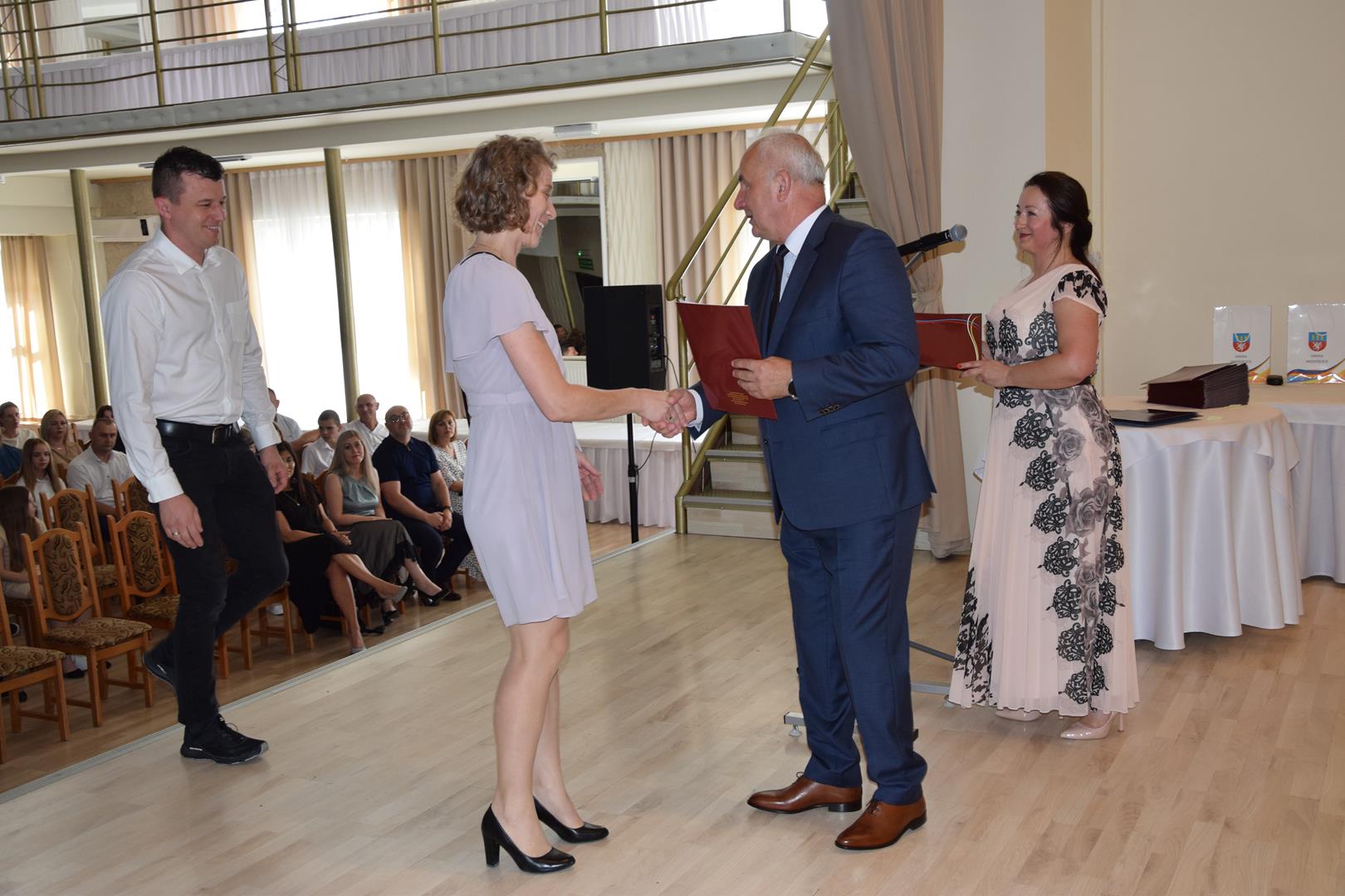 Zdjęcie przedstawia moment wręczenia dyplomów z okazji promocji ucznia zdolnego 2024