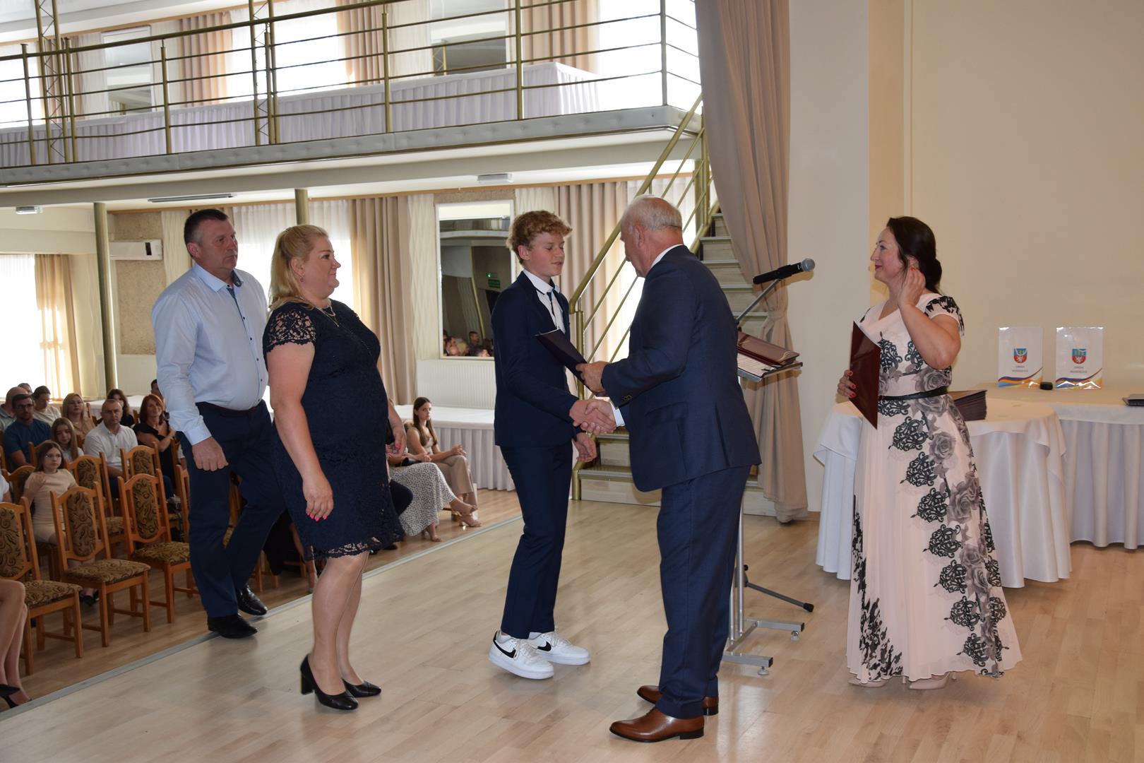Zdjęcie przedstawia moment wręczenia dyplomów z okazji promocji ucznia zdolnego 2024