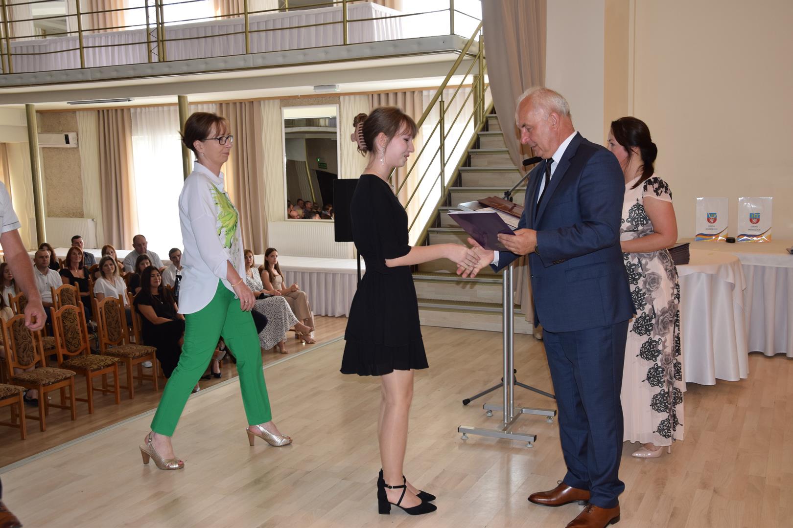 Zdjęcie przedstawia moment wręczenia dyplomów z okazji promocji ucznia zdolnego 2024