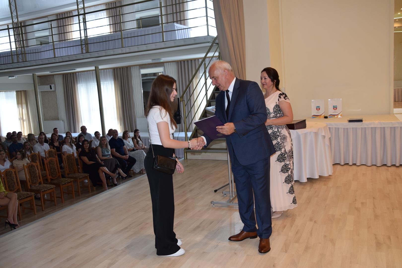 Zdjęcie przedstawia moment wręczenia dyplomów z okazji promocji ucznia zdolnego 2024