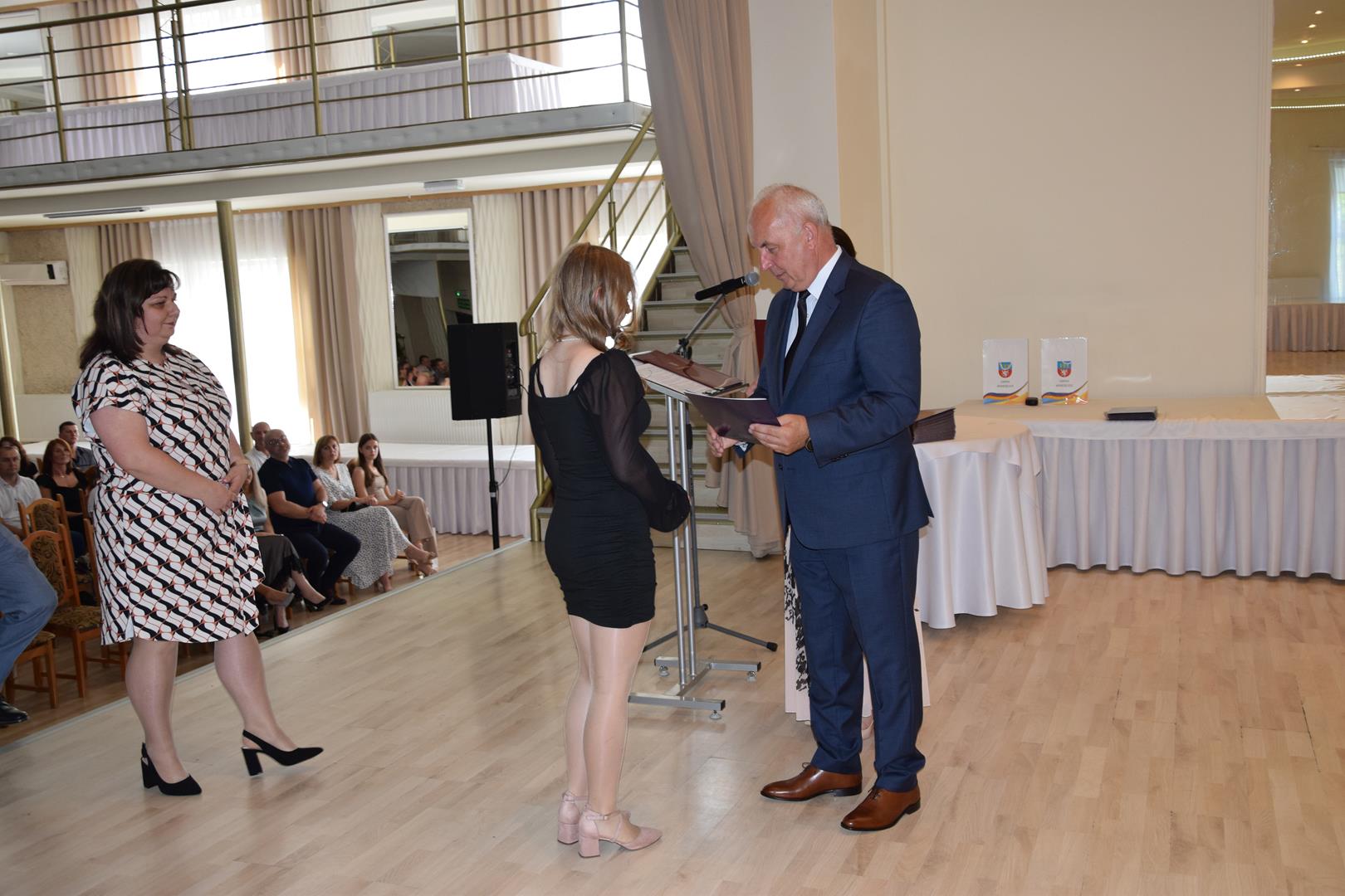Zdjęcie przedstawia moment wręczenia dyplomów z okazji promocji ucznia zdolnego 2024