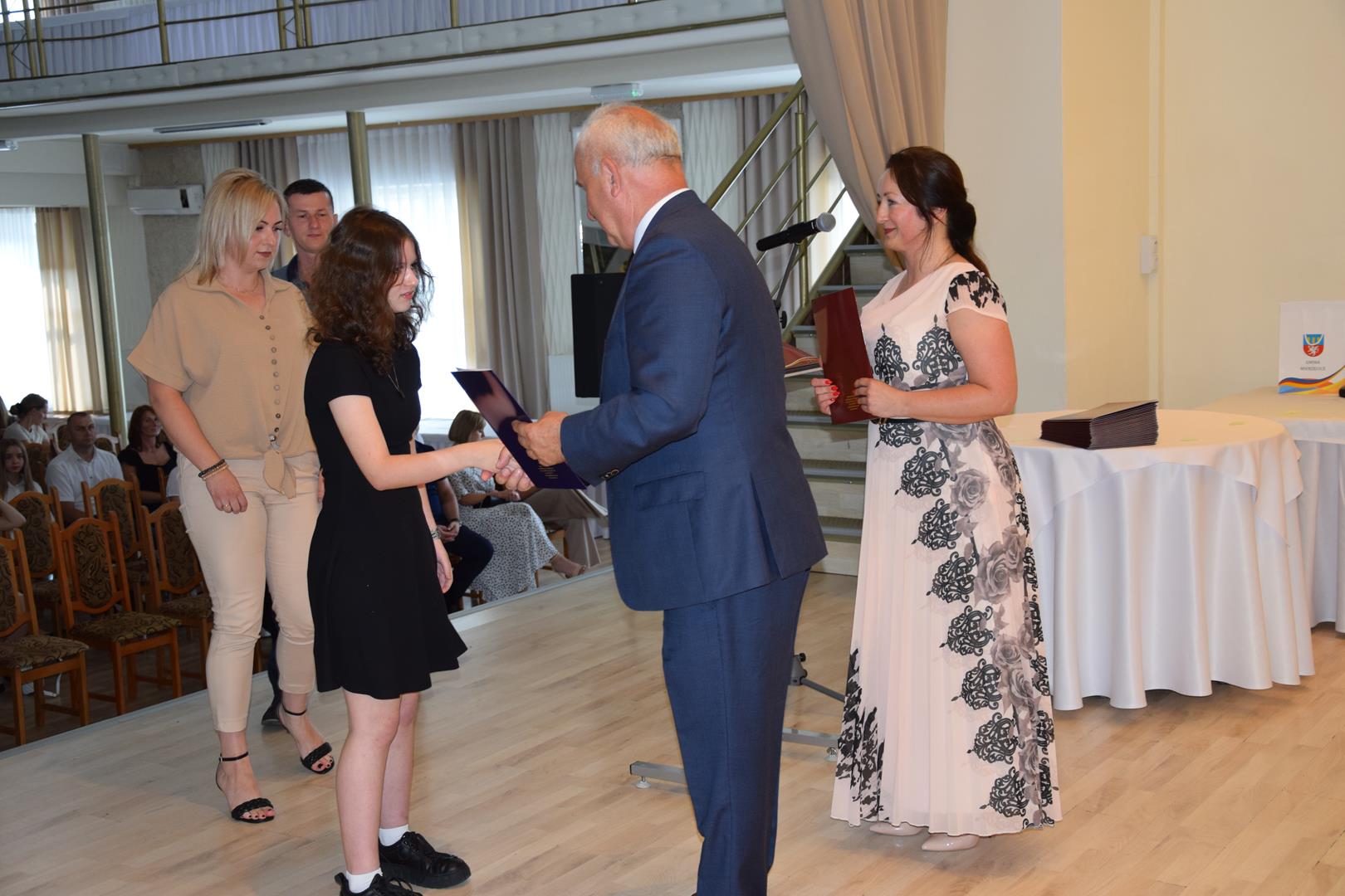 Zdjęcie przedstawia moment wręczenia dyplomów z okazji promocji ucznia zdolnego 2024