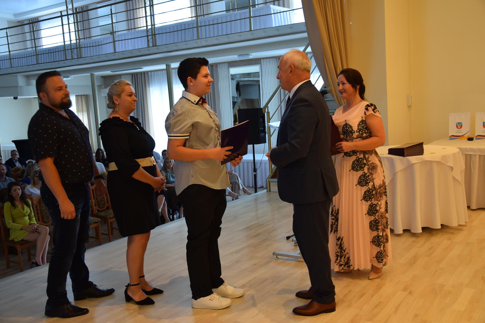 Zdjęcie przedstawia moment wręczenia dyplomów z okazji promocji ucznia zdolnego 2024