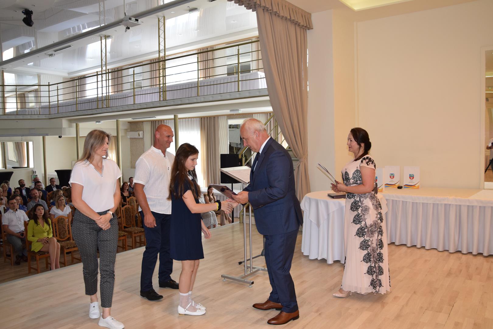 Zdjęcie przedstawia moment wręczenia dyplomów z okazji promocji ucznia zdolnego 2024