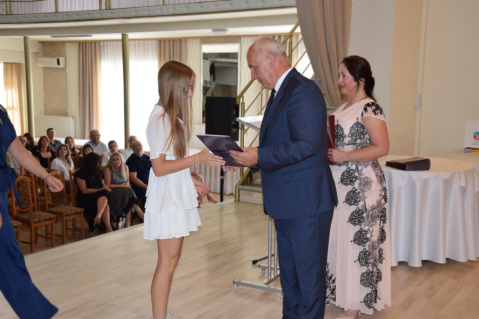 Zdjęcie przedstawia moment wręczenia dyplomów z okazji promocji ucznia zdolnego 2024