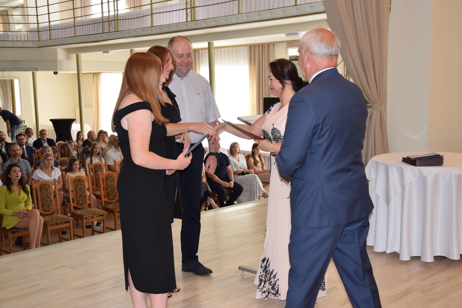 Zdjęcie przedstawia moment wręczenia dyplomów z okazji promocji ucznia zdolnego 2024