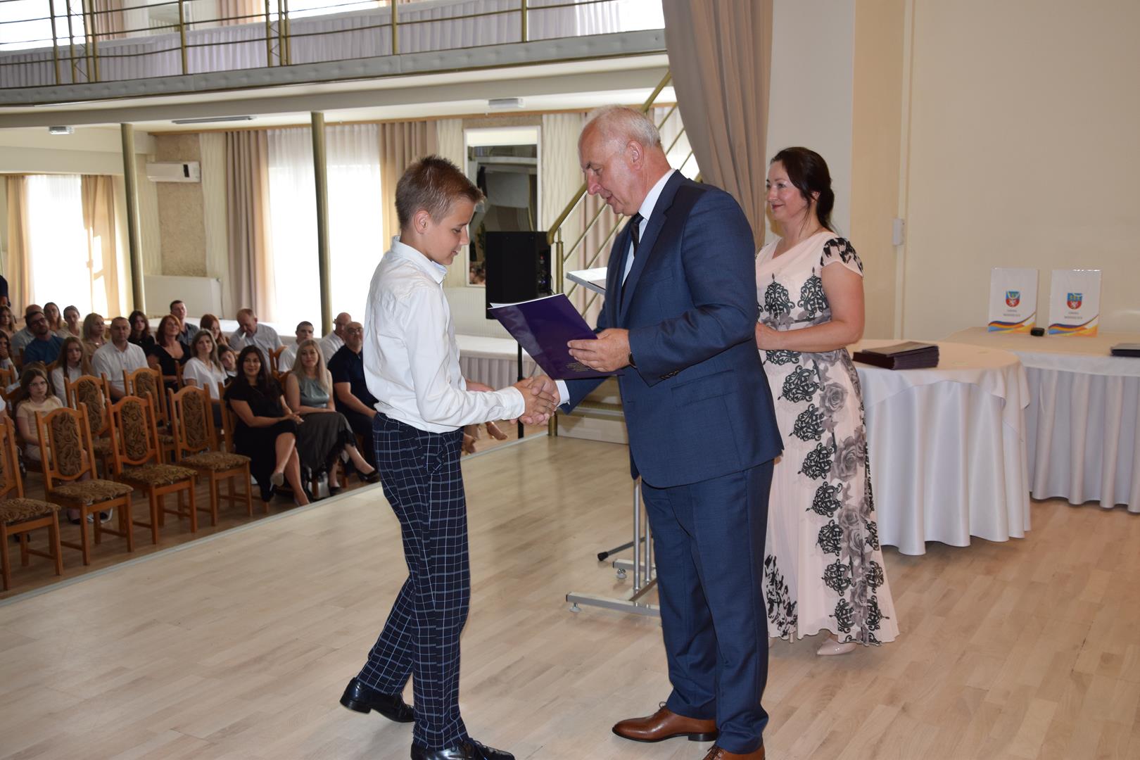 Zdjęcie przedstawia moment wręczenia dyplomów z okazji promocji ucznia zdolnego 2024
