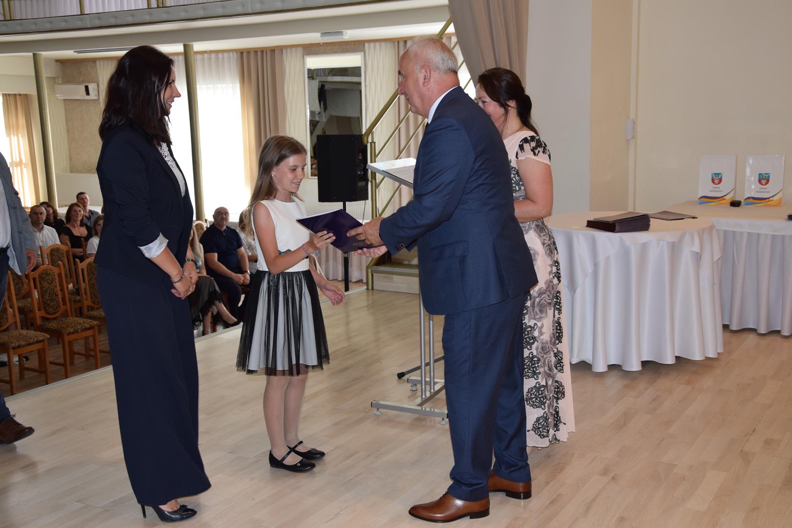 Zdjęcie przedstawia moment wręczenia dyplomów z okazji promocji ucznia zdolnego 2024