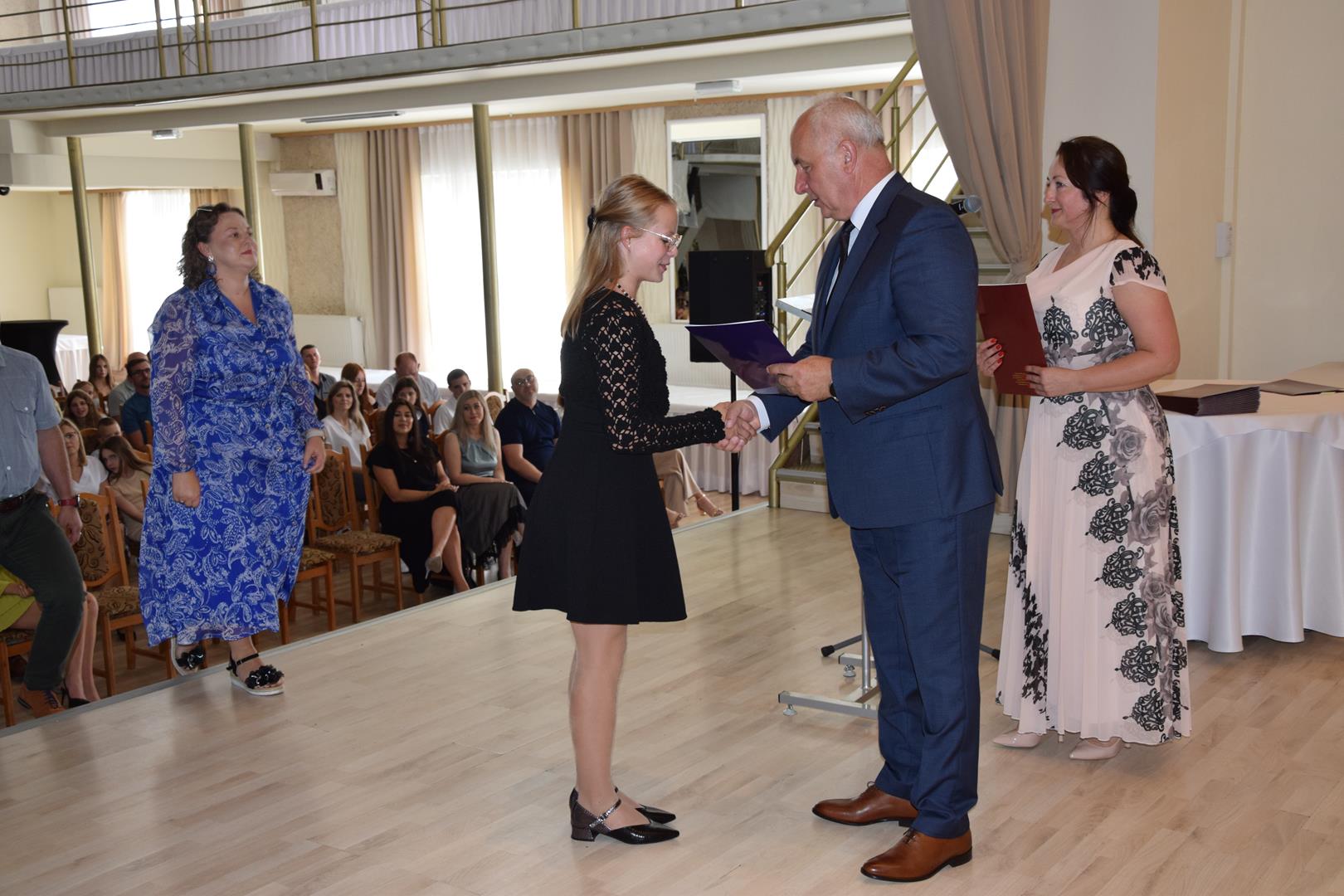 Zdjęcie przedstawia moment wręczenia dyplomów z okazji promocji ucznia zdolnego 2024