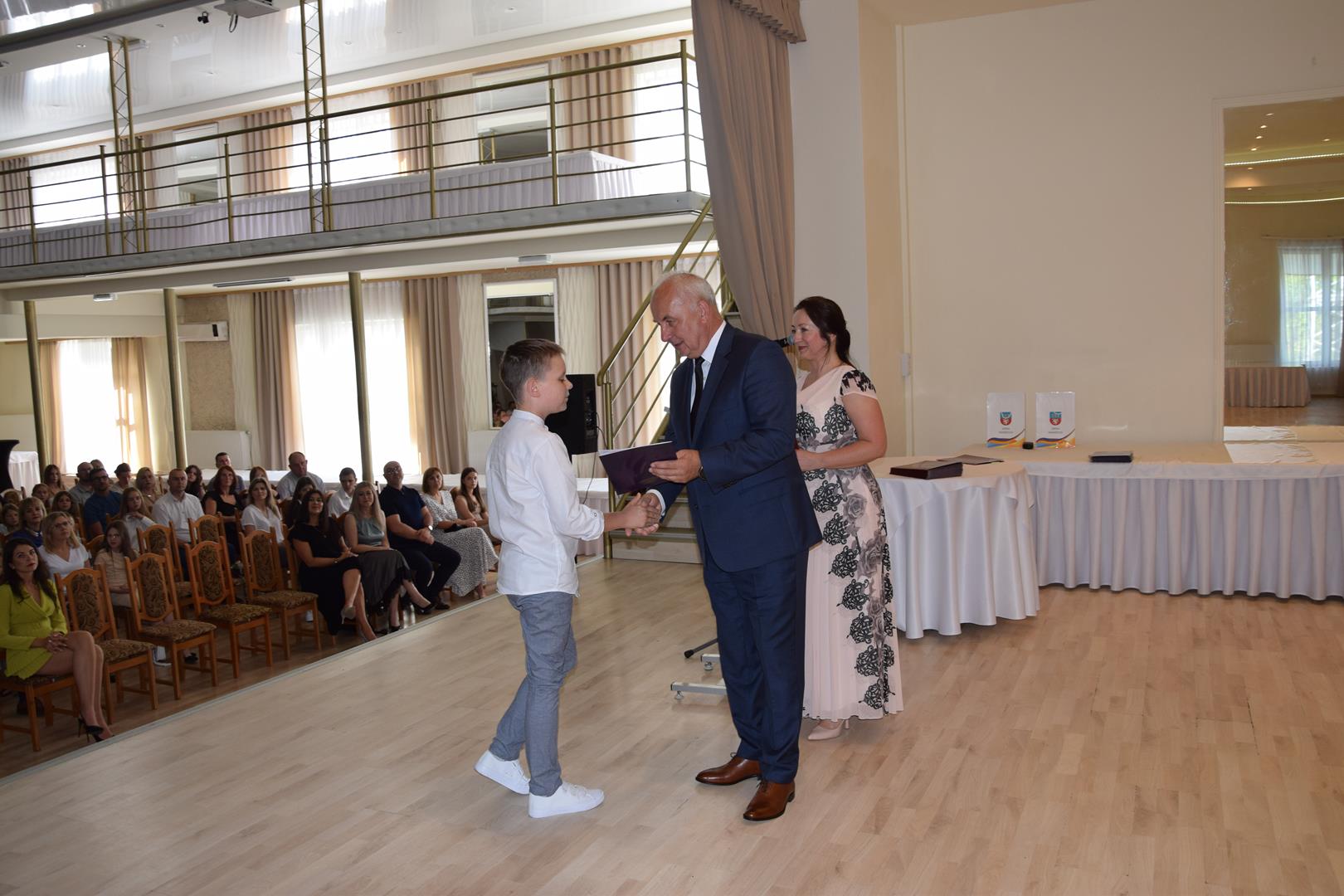 Zdjęcie przedstawia moment wręczenia dyplomów z okazji promocji ucznia zdolnego 2024