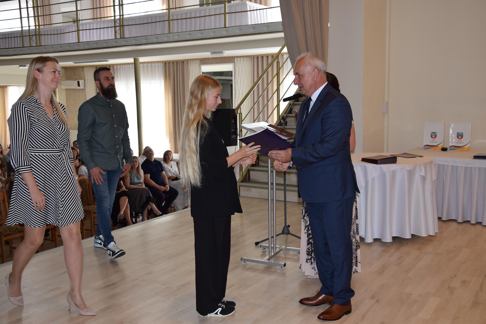 Zdjęcie przedstawia moment wręczenia dyplomów z okazji promocji ucznia zdolnego 2024