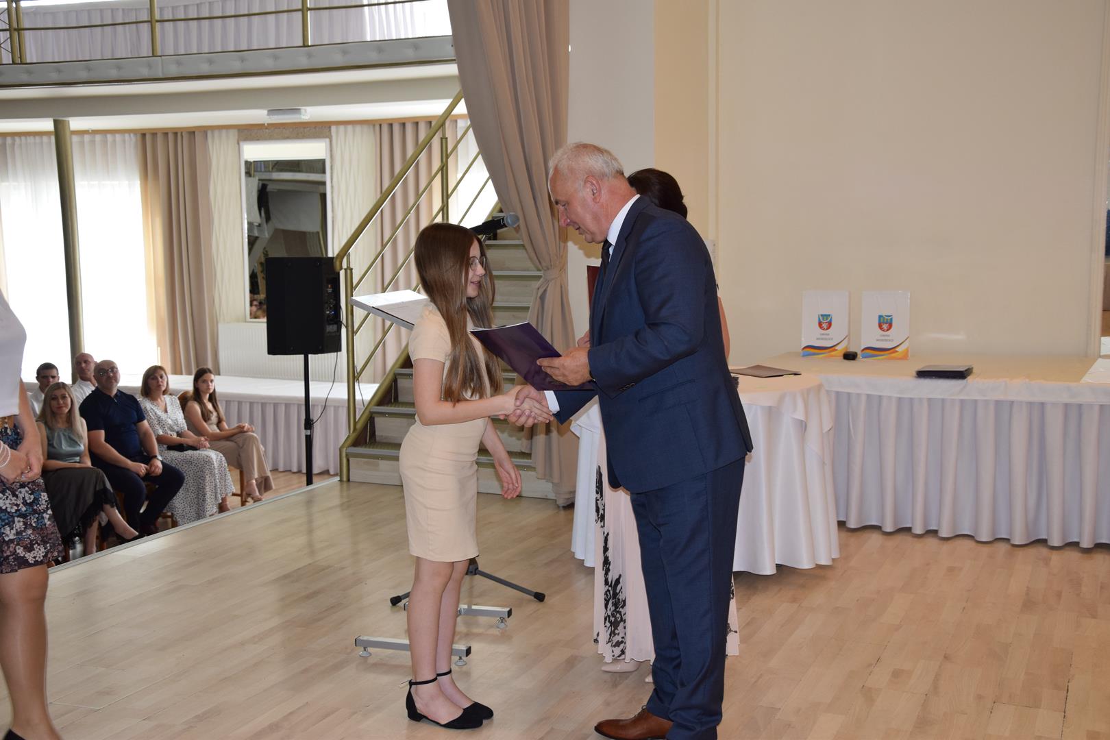 Zdjęcie przedstawia moment wręczenia dyplomów z okazji promocji ucznia zdolnego 2024