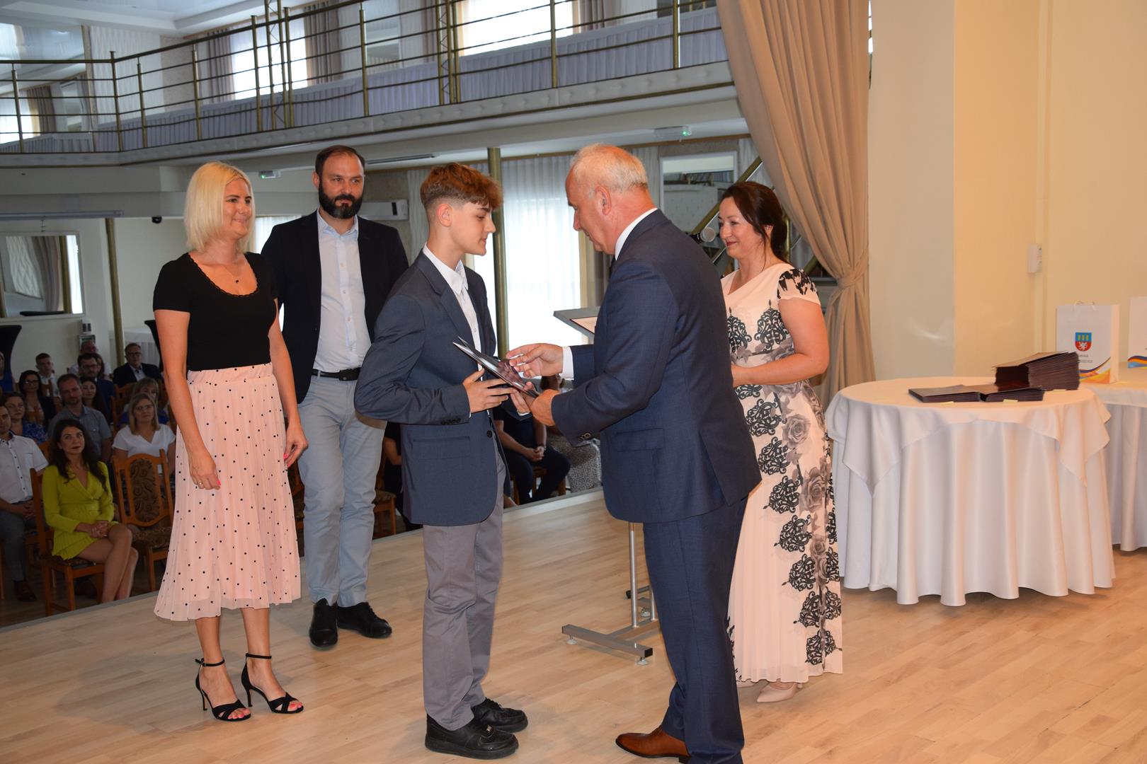 Zdjęcie przedstawia moment wręczenia dyplomów z okazji promocji ucznia zdolnego 2024