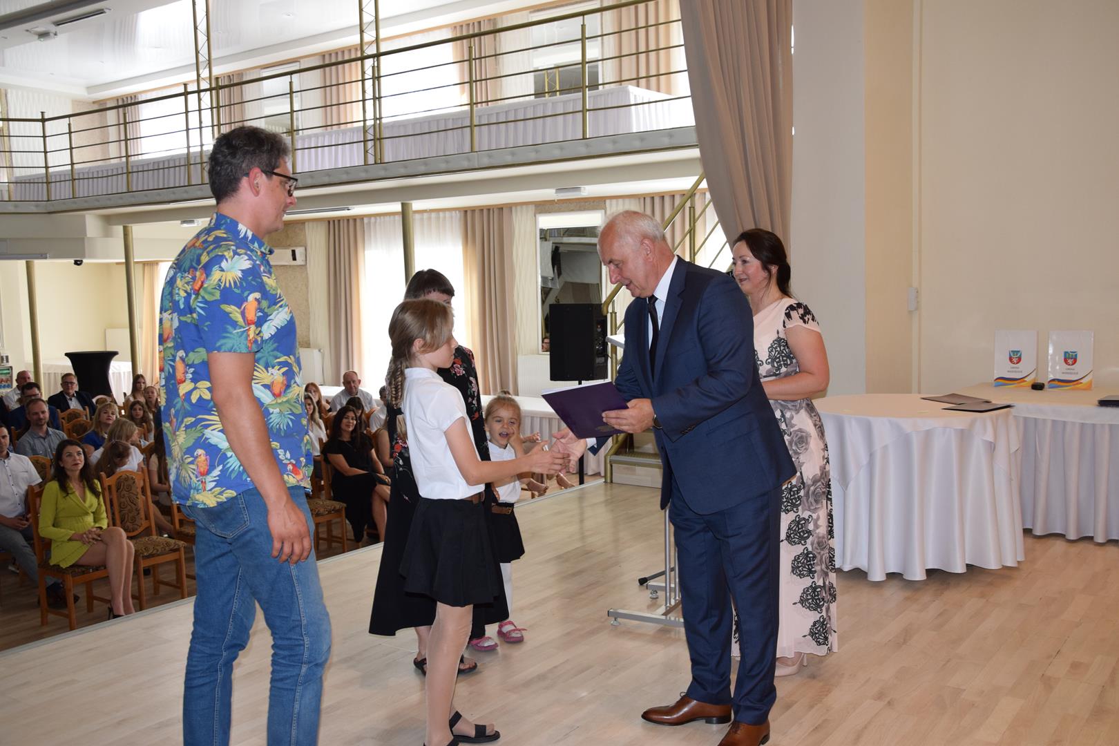 Zdjęcie przedstawia moment wręczenia dyplomów z okazji promocji ucznia zdolnego 2024