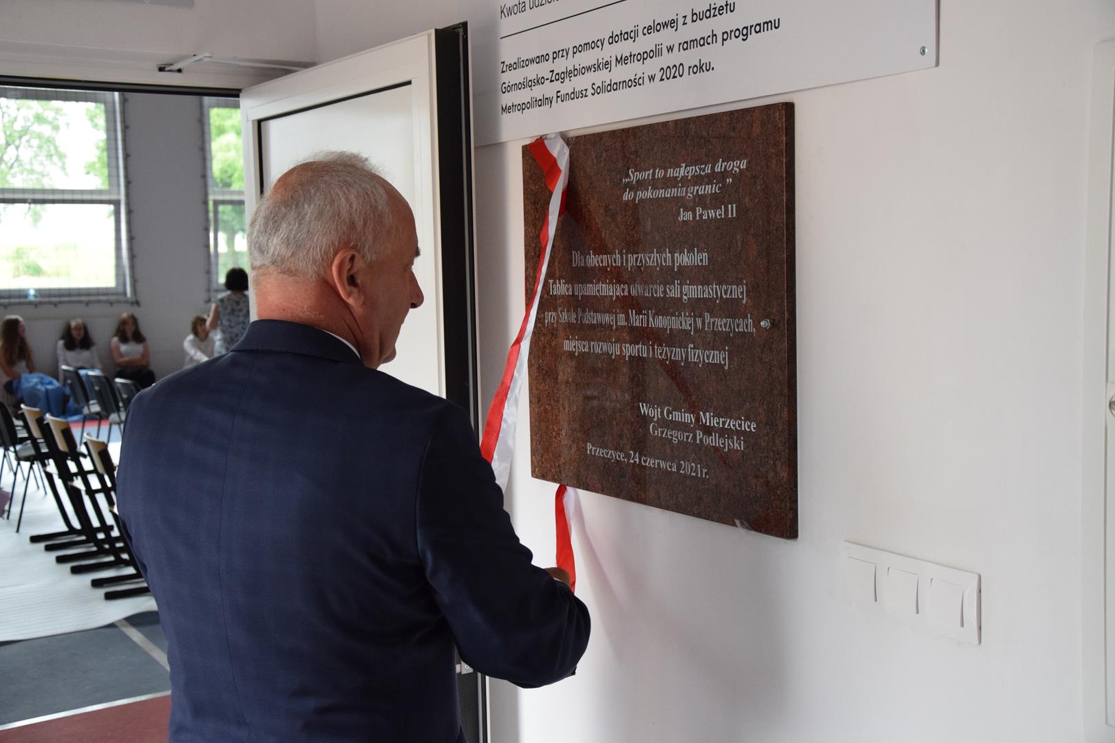 Zdjęcie przedstawiające moment odsłonięcia pamiątkowej tablicy przez Wójta Gminy Mierzęcice Grzegorza Podlejskiego