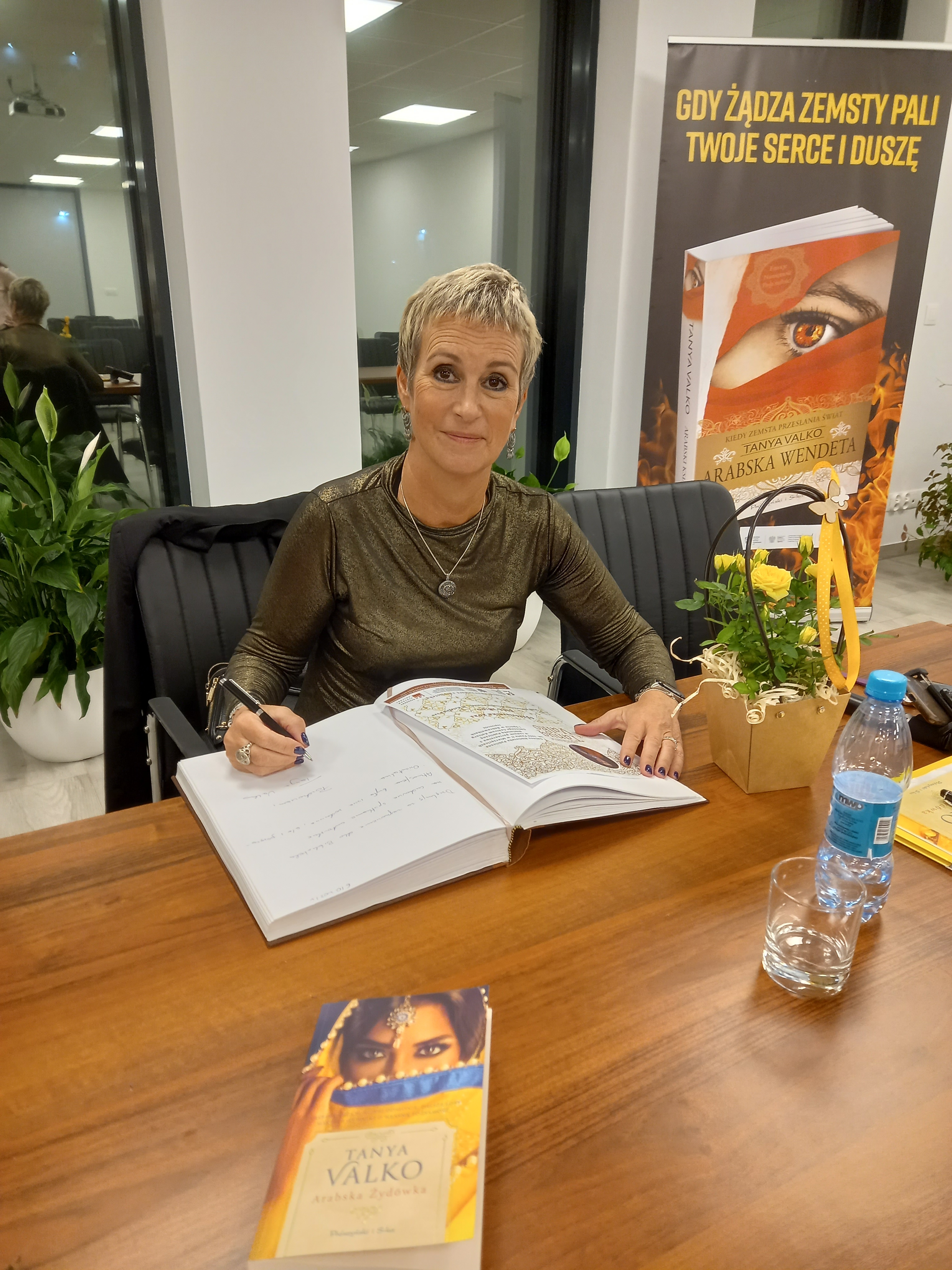 Zdjęcie przedstawiające autorkę podpisującą książki