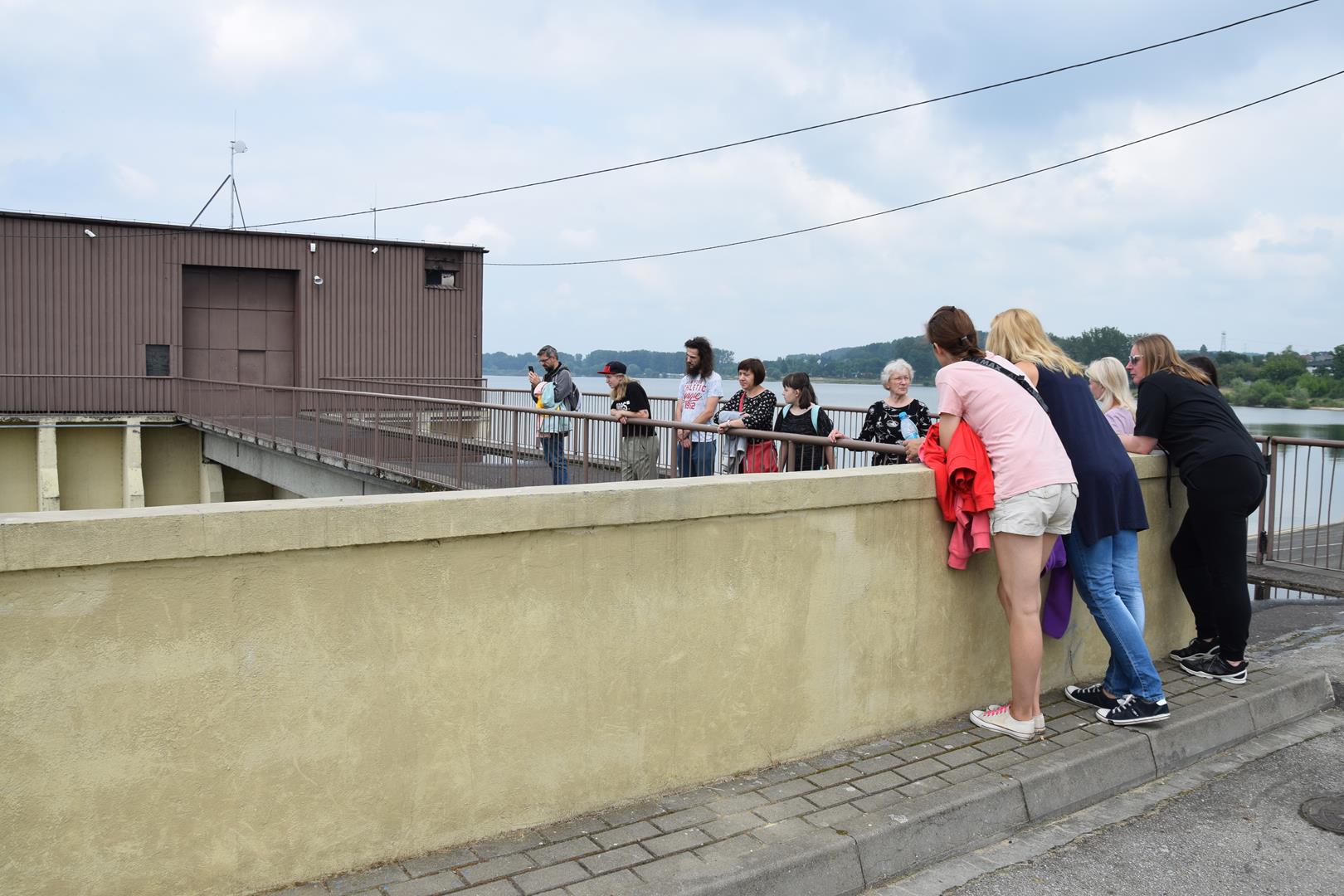 Zdjęcie przedstawiające uczestników wycieczki spoglądających na zaporę